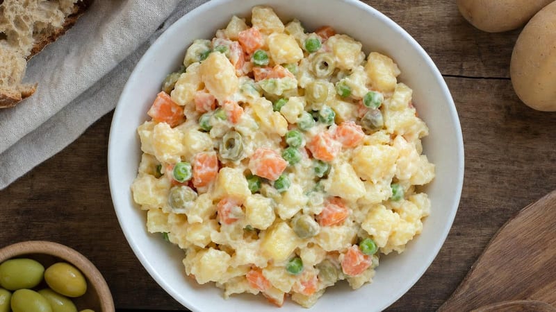 Bol de ensaladilla vegana con zanahoria, guisantes y aceitunas