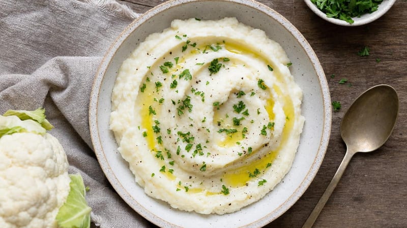 Cuenco de puré de coliflor cremoso con aceite y perejil