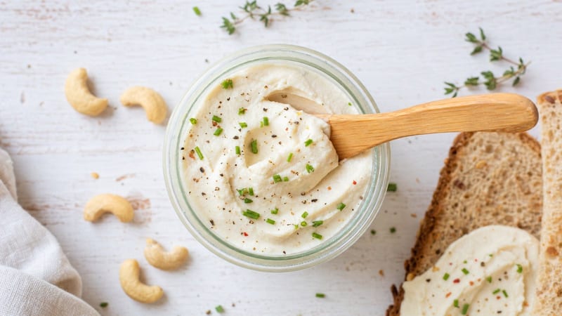 Tarro de queso crema vegano de anacardos con un cuchillo de untar